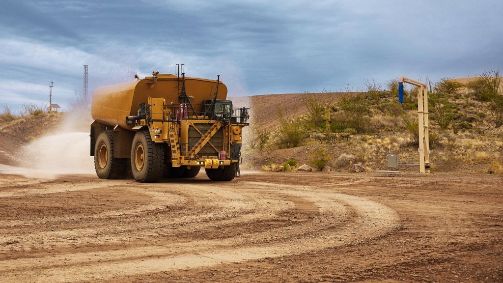 A large yellow truck driving down a dirt road