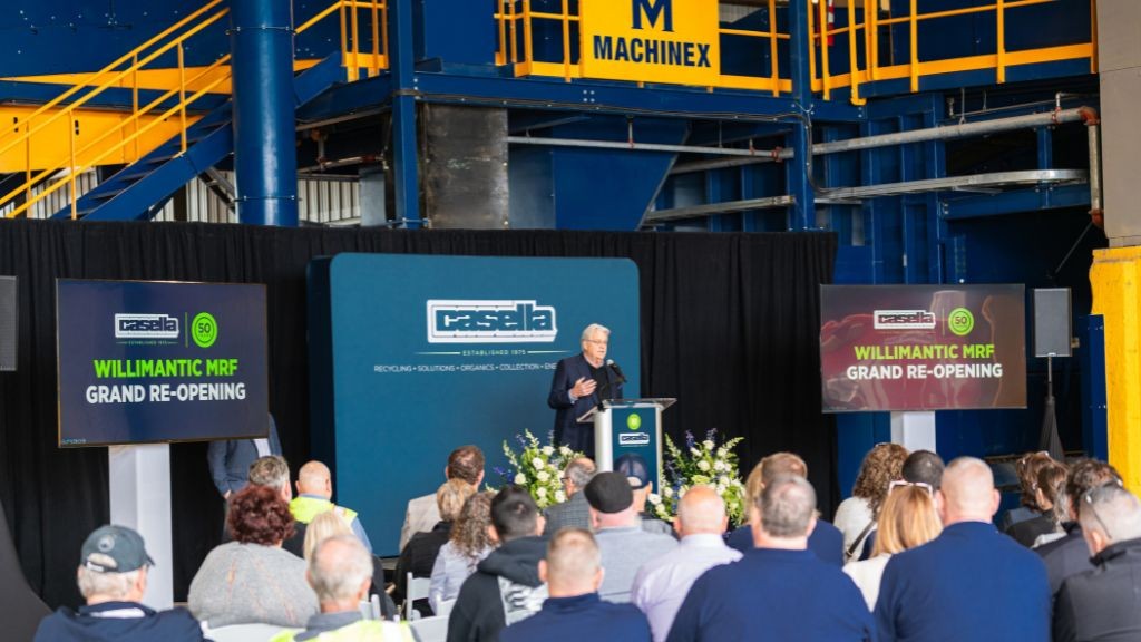A man stands at a podium addressing a small audience at a facility opening A man stands at a podium addressing a small audience at a facility opening