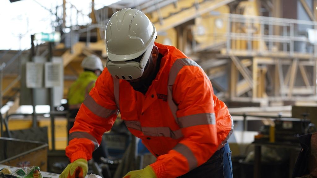 A recycling plant worker wearing a VR headset and an orange jacket A recycling plant worker wearing a VR headset and an orange jacket