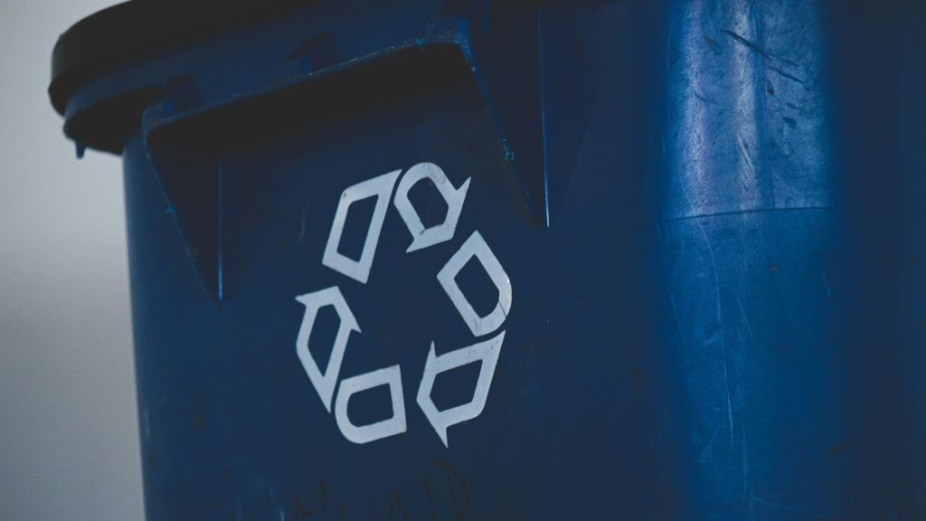 A blue recycling container with the white recycling logo A blue recycling container with the white recycling logo