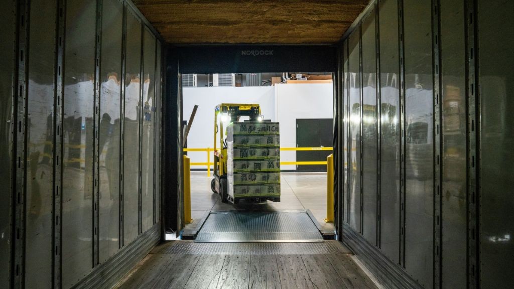 A forklift moving a large pallet into a shipping container A forklift moving a large pallet into a shipping container
