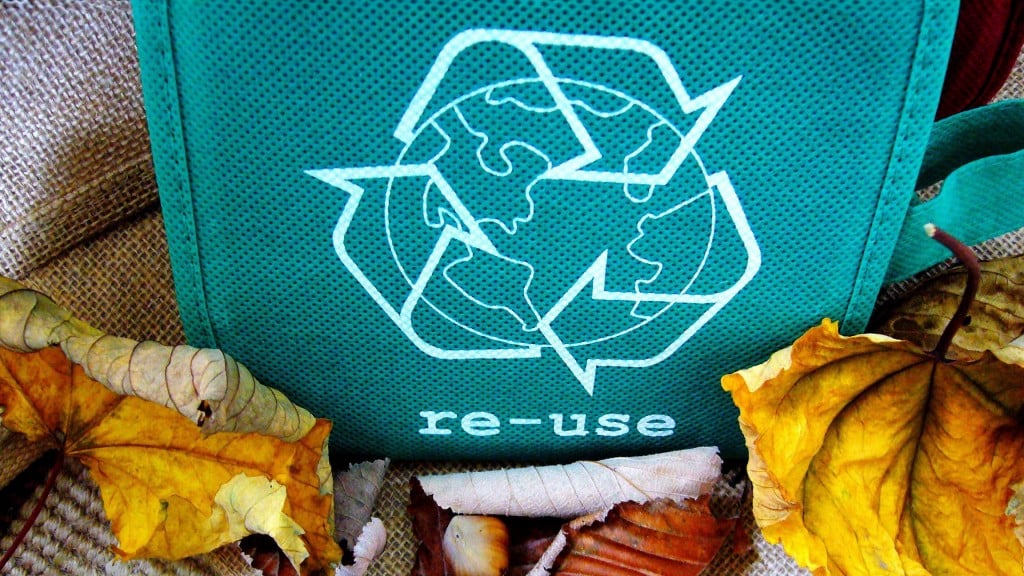 A small tote bag with a recycling logo next to plastic packaging A small tote bag with a recycling logo next to plastic packaging