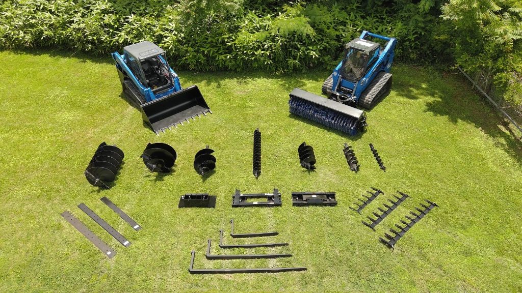 Two tractors with several replacement parts laid out on the grass next to them