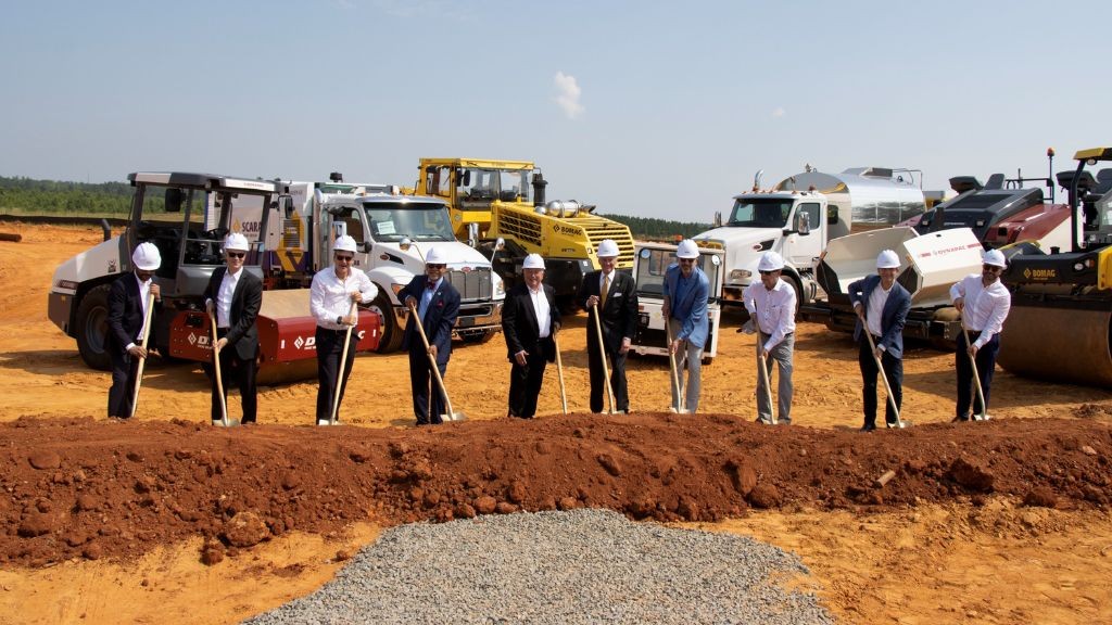 Several men wearing suits and hardhats ceremoniously dig into a new site Several men wearing suits and hardhats ceremoniously dig into a new site