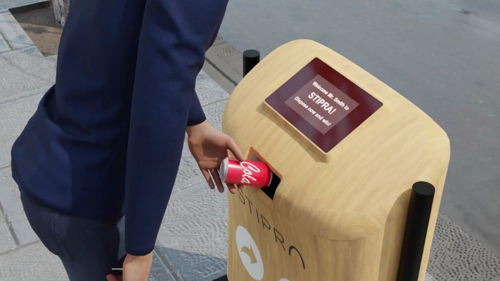 A man placing a tin soda can into a robotic recycling bin A man placing a tin soda can into a robotic recycling bin