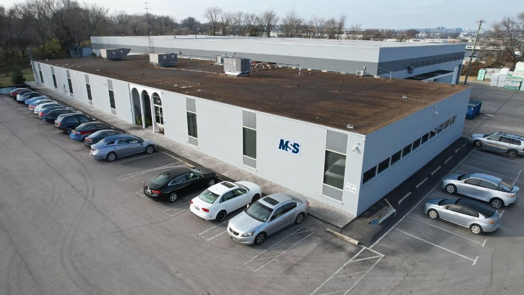 An aerial view of a large warehouse surrounded by cars in the parking lot An aerial view of a large warehouse surrounded by cars in the parking lot