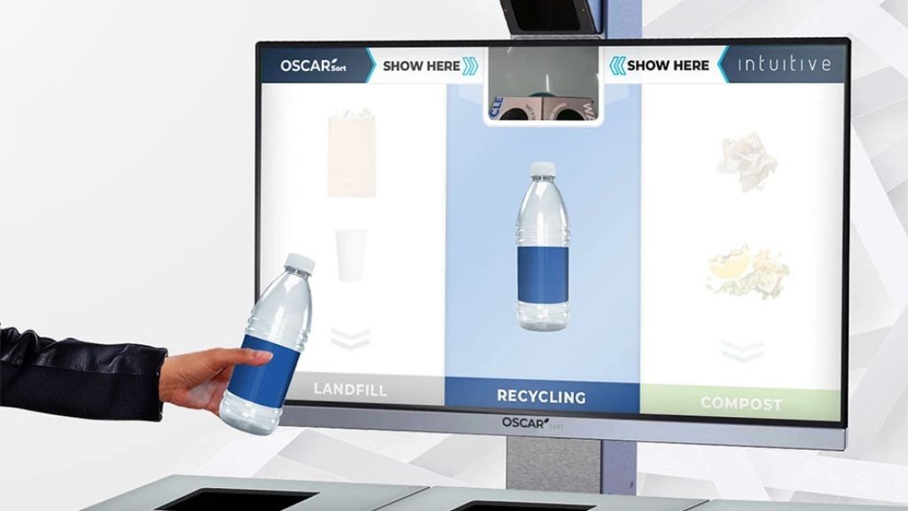 A TV screen with several images of recycling containers with a person holding a plastic bottle up to the screen A TV screen with several images of recycling containers with a person holding a plastic bottle up to the screen