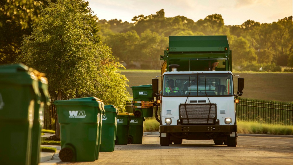 A refuse collection truck next to several green recycling bins A refuse collection truck next to several green recycling bins