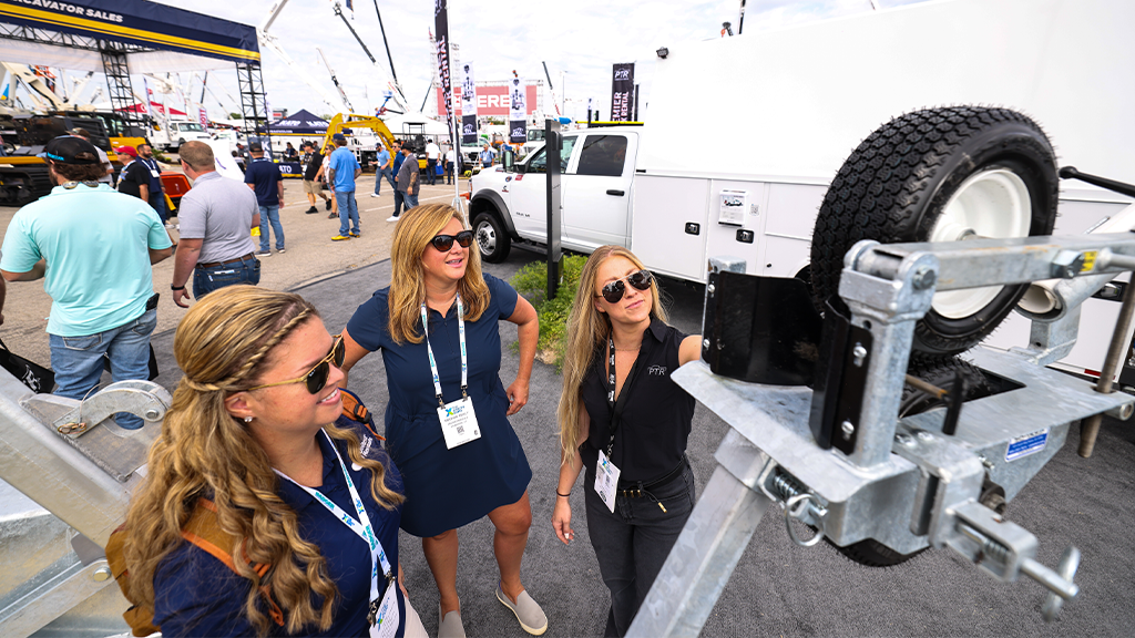 Three women standing in a trade show outdoor area