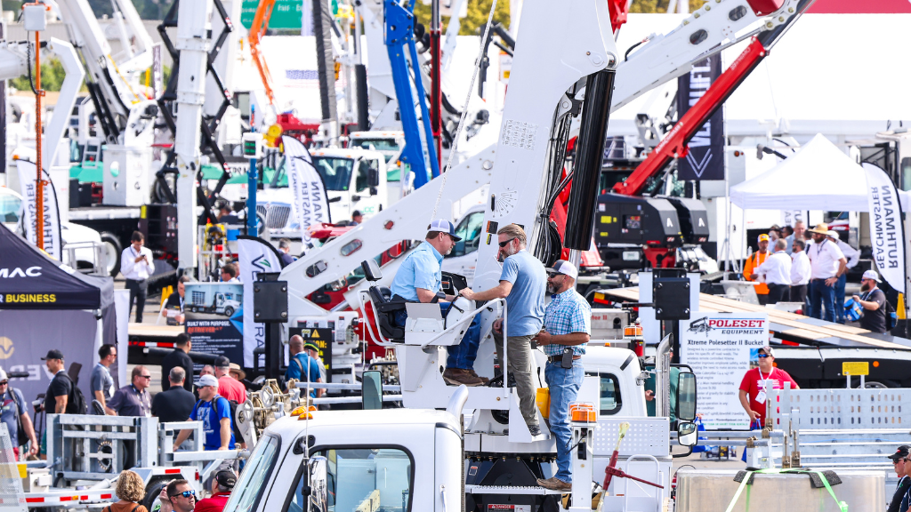 A group of men looking at large equipment at an outdoor trade show A group of men looking at large equipment at an outdoor trade show