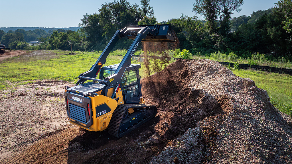 A compact track loader with its arm and bucket fully extended