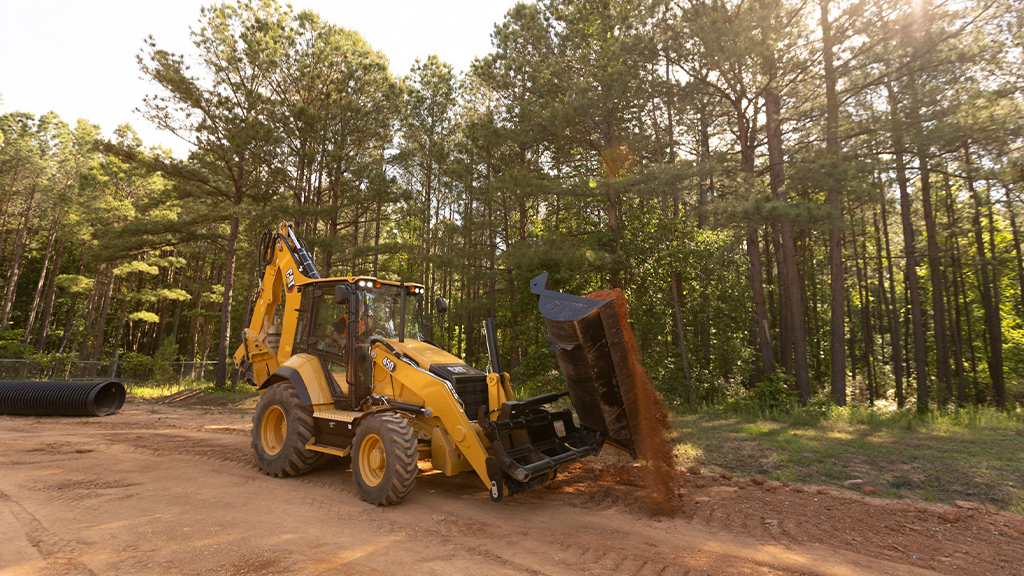 A yellow backhoe loader on the side of the road