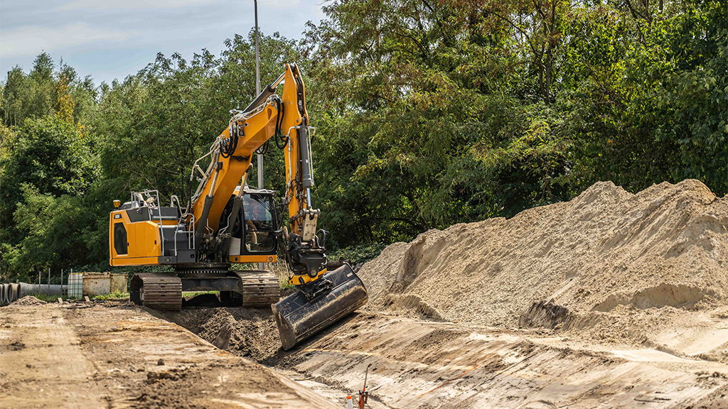 A yellow excavator working in a ditch A yellow excavator working in a ditch