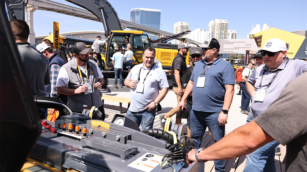 A group of people standing at a piece of heavy equipment machinery A group of people standing at a piece of heavy equipment machinery