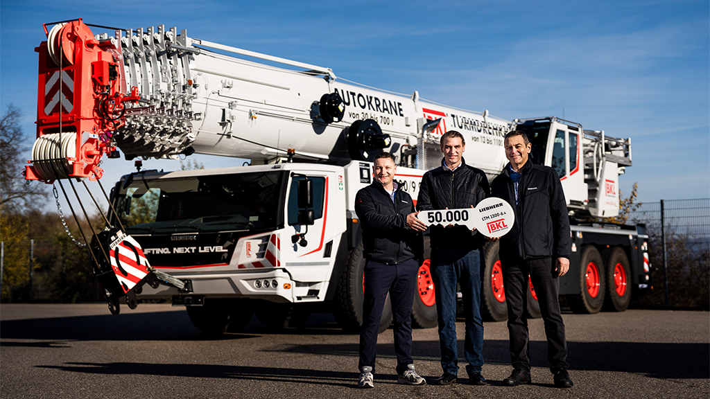 Three men holding a large key standing in front of a mobile crane Three men holding a large key standing in front of a mobile crane