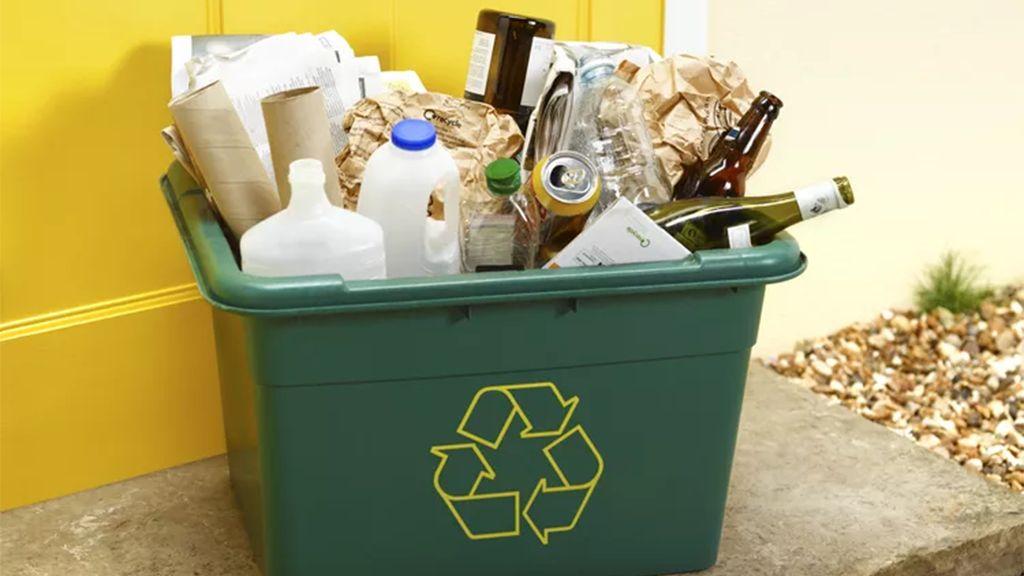 A green recycling bin filled with loose containers A green recycling bin filled with loose containers