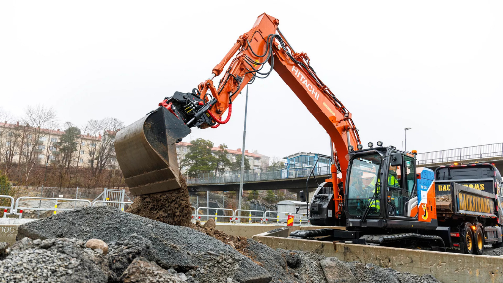 An excavator pours dirt from its bucket on an outdoor construction site
