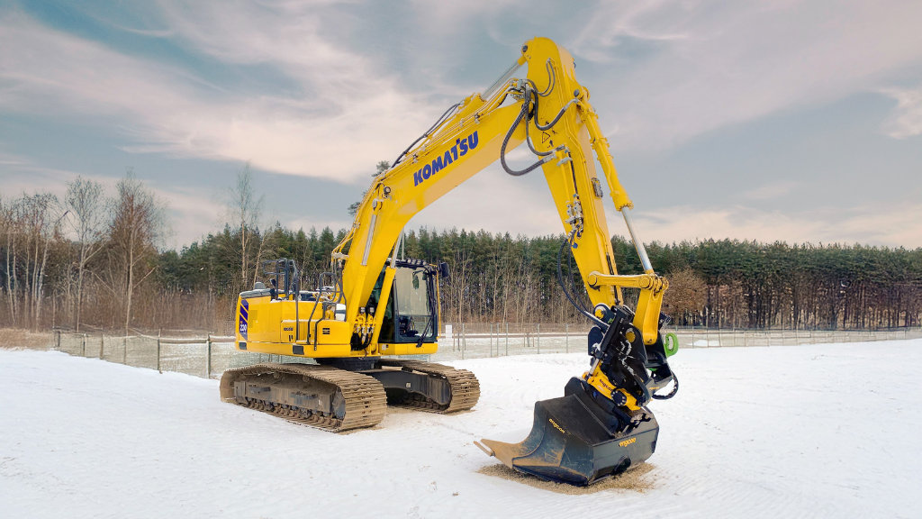 A yellow excavator in the snow with a bucket attachment