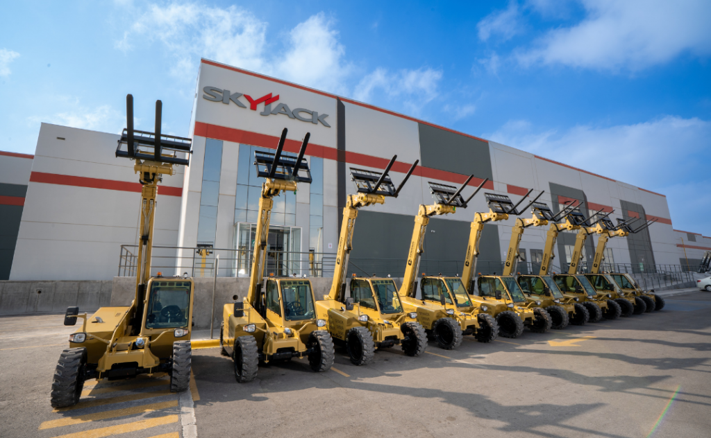Several hold painted telehandlers parked in a row in front of a warehouse Several hold painted telehandlers parked in a row in front of a warehouse