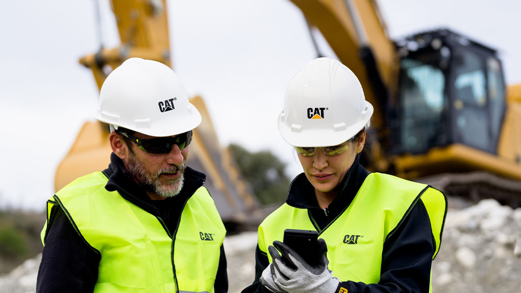 Two people wear hard hats and high-vis vests on a construction site Two people wear hard hats and high-vis vests on a construction site