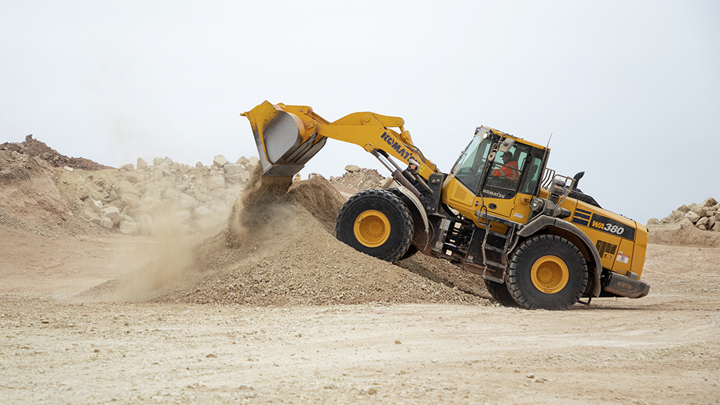 A wheel loader dumps its bucket filled with aggregates