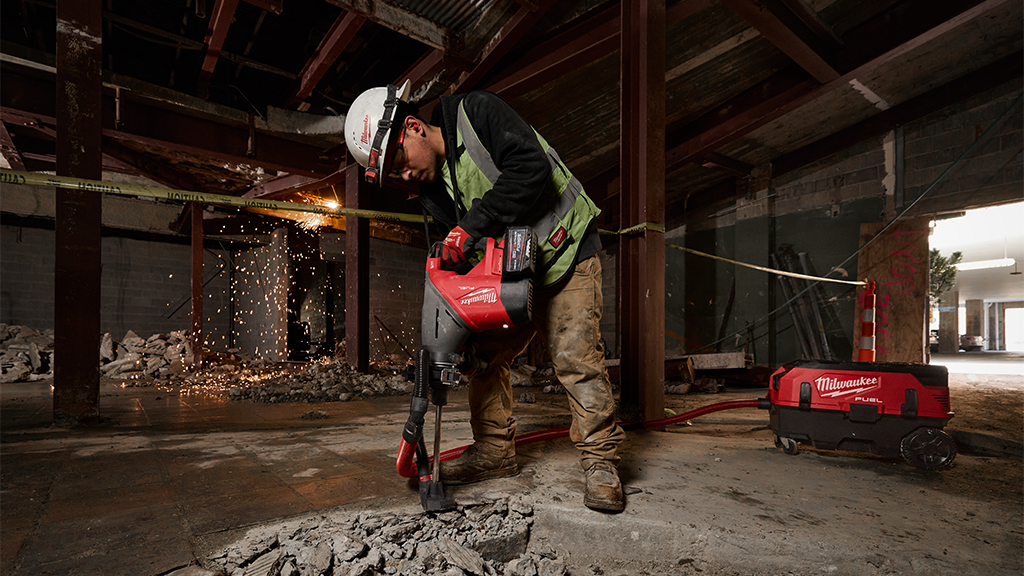 A man operating a demolition hammer inside a job site