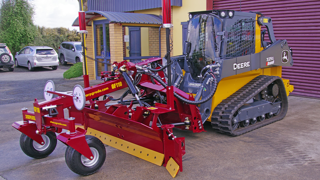 A John Deere CTL fitted with a large red grader blade A John Deere CTL fitted with a large red grader blade