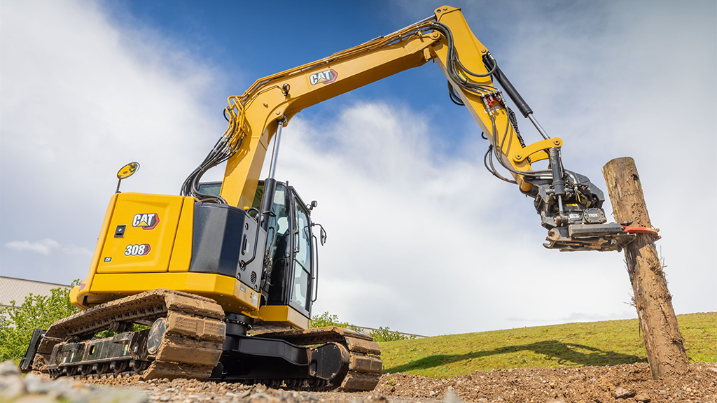 A mini excavator uses an attachment to take a pole out of the ground