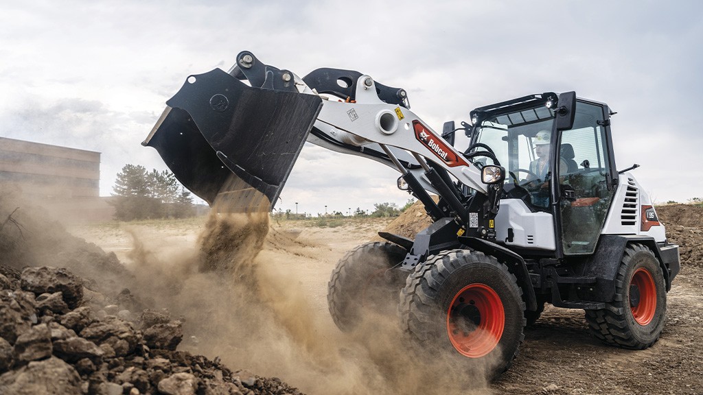 A compact wheel loader dumps aggregates with a bucket attachment
