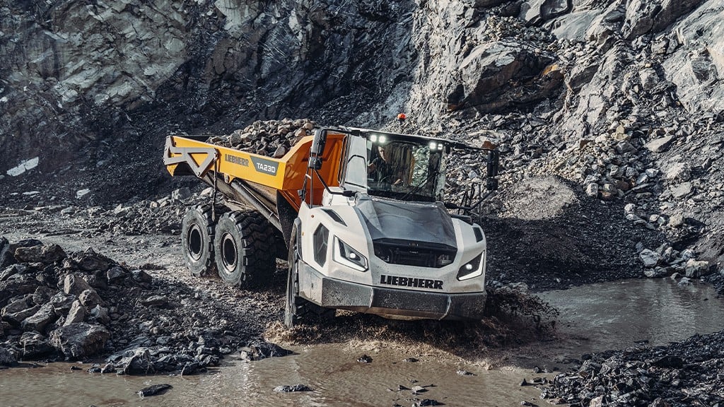An articulated dump truck filled with aggregates driving through a quarry site An articulated dump truck filled with aggregates driving through a quarry site
