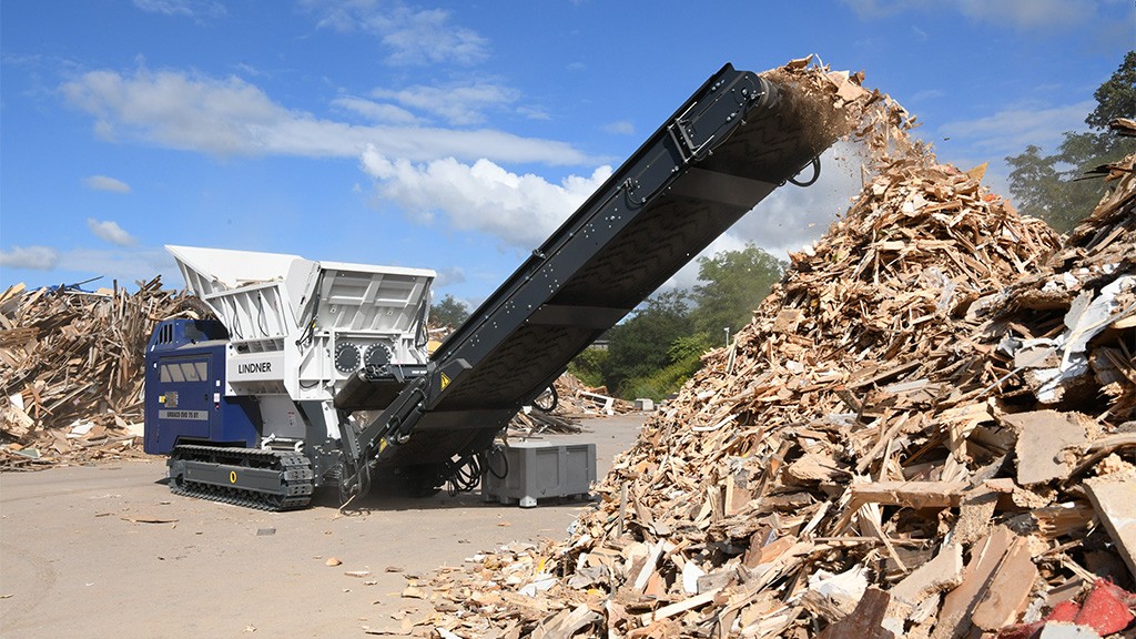 A large wood shredder extrudes a pile of chips A large wood shredder extrudes a pile of chips