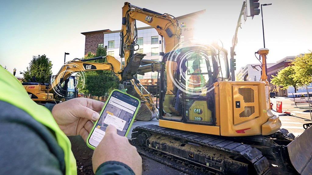 A man operating a phone in front of an excavator