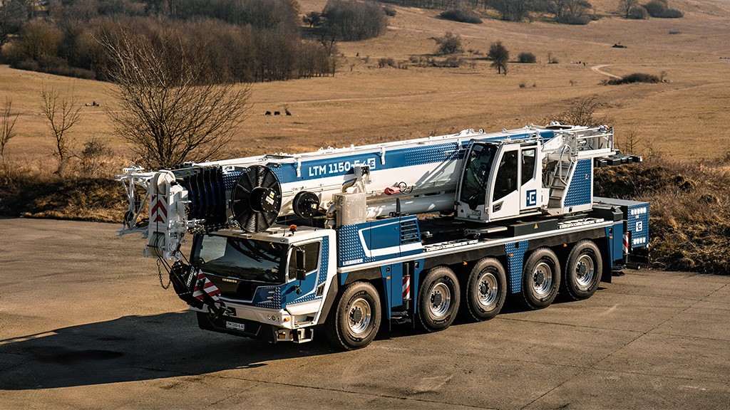 A mobile crane truck parked on a dry grassy area A mobile crane truck parked on a dry grassy area
