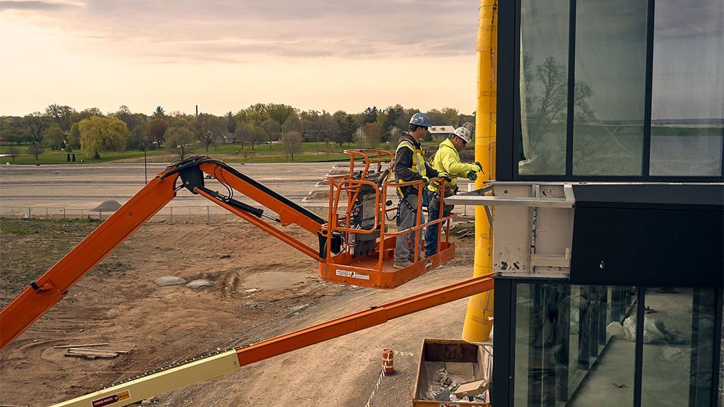 Two men in the basket of a boom lift working on the side of a building