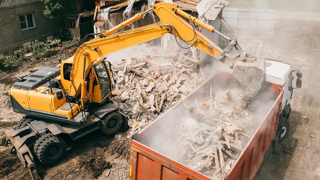 An excavator loads a container of C&D materials