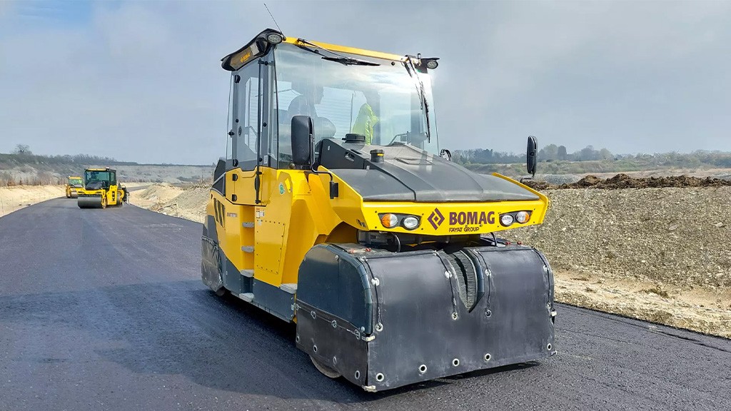 A pneumatic tire roller on a freshly paved asphalt road