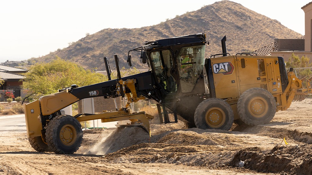 A motor grader works grading a small mound of earth