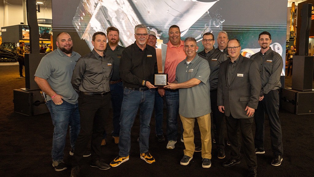 A group of men take a photo with an award