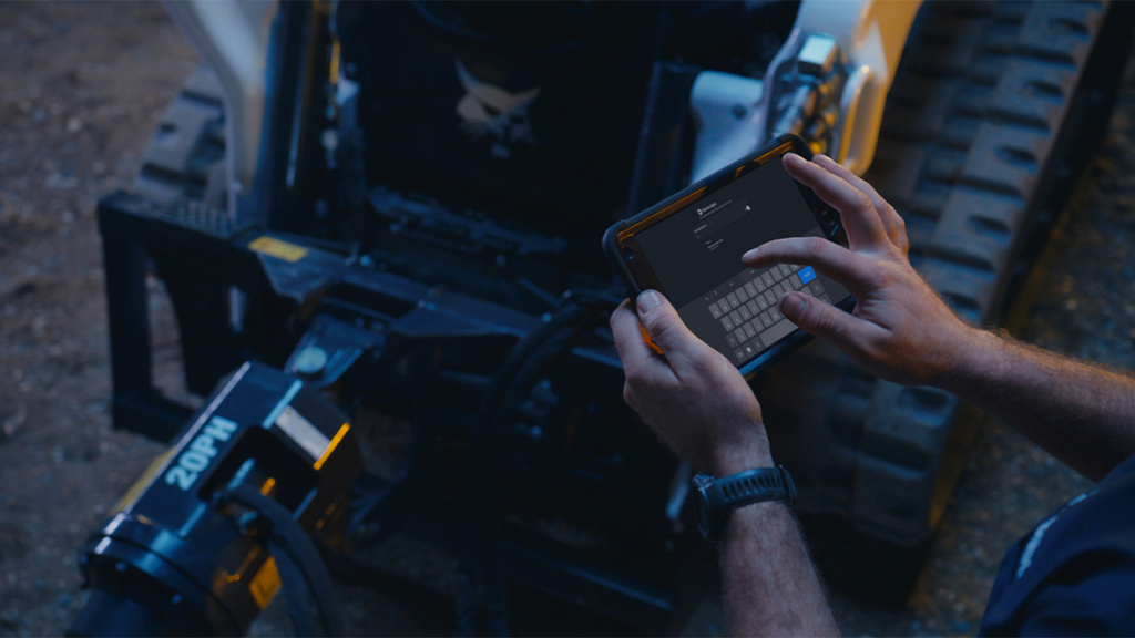 A person operates a tablet in front of a compact machine A person operates a tablet in front of a compact machine