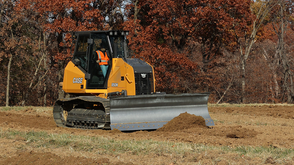 A man operates a dozer in a dry grassy field A man operates a dozer in a dry grassy field