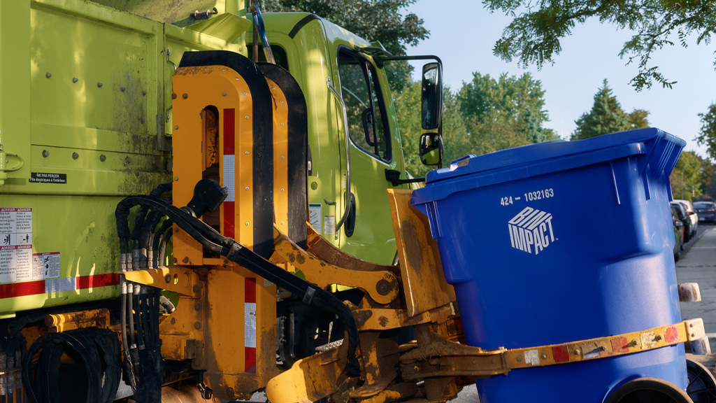 A green collection vehicle picks up a blue recycling bin