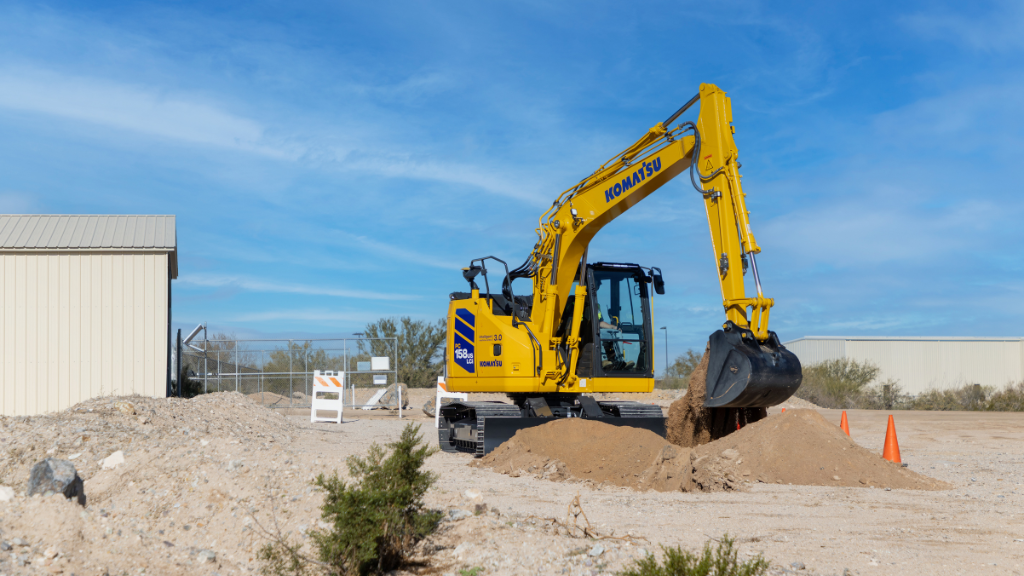 An excavator uses its bucket attachment to dig in light soil