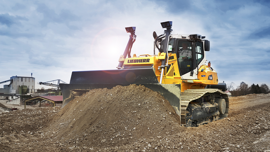 A dozer fitted with pushes a pile of dirt