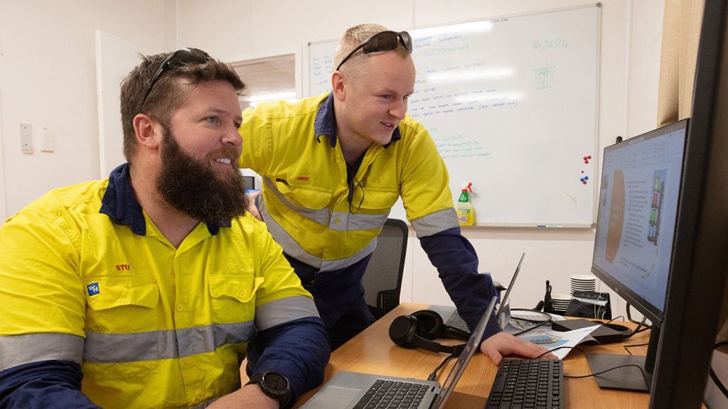 Two men look at a computer screen