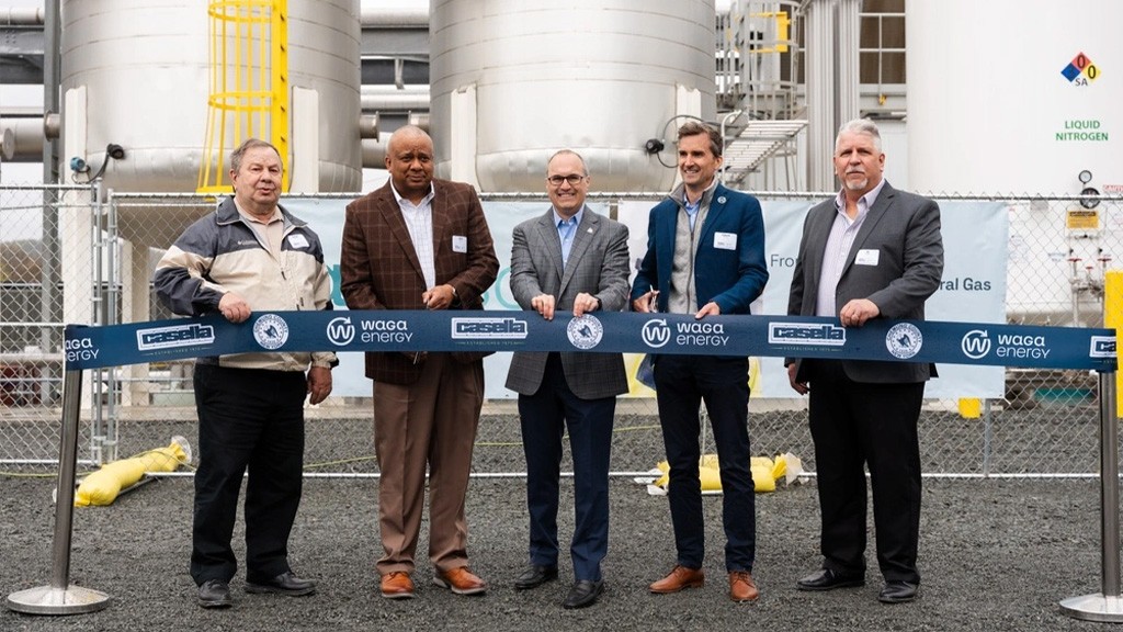 A group of men stand in front of a large ribbon A group of men stand in front of a large ribbon