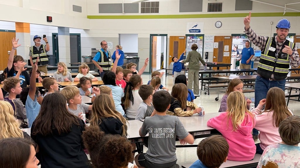 Kids in a cafeteria with a few men wearing full PPE Kids in a cafeteria with a few men wearing full PPE