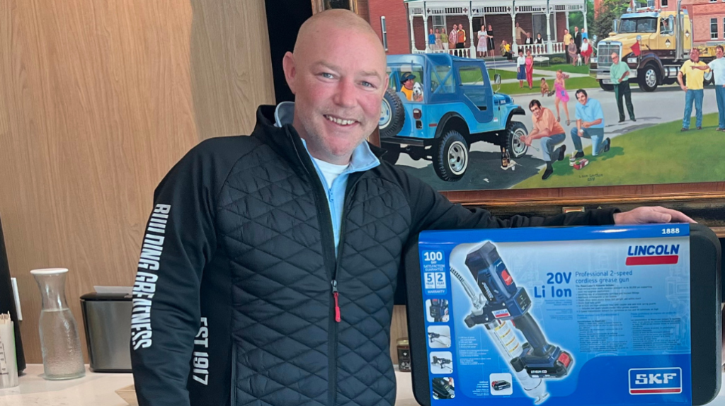 A man poses with a lubricating gun in a box
