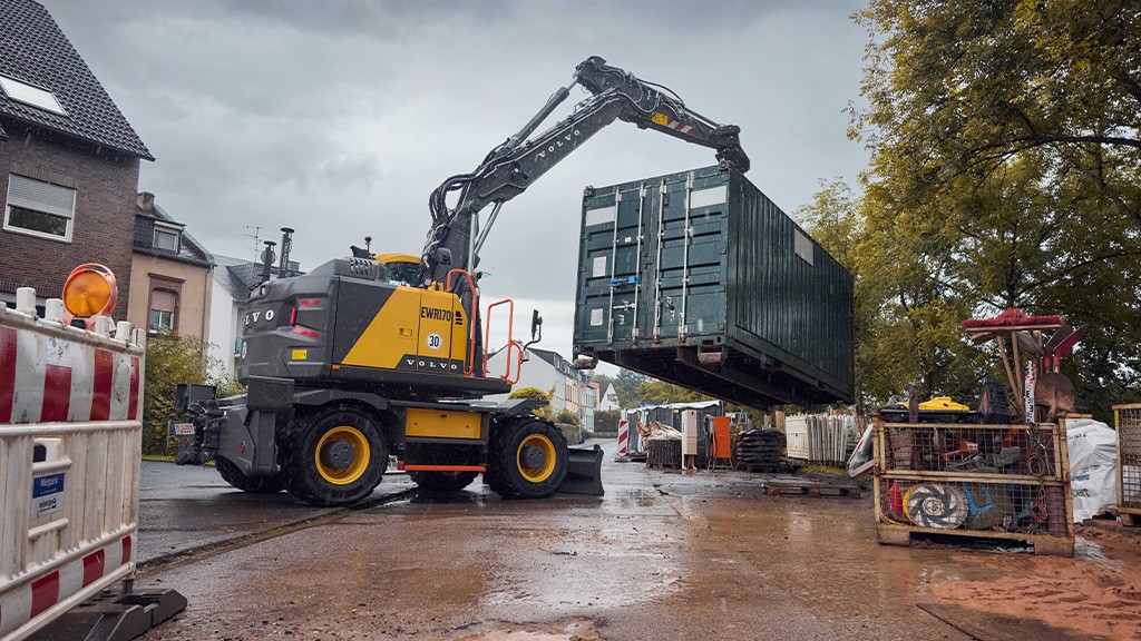 A crawler excavator lifts a shipping container