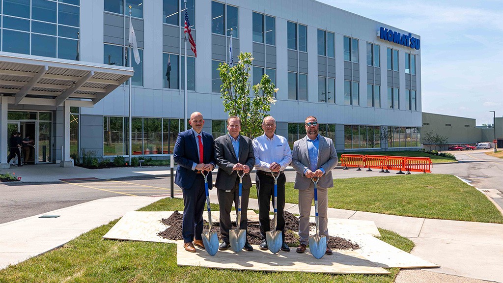 Four men hold shovels in front of a newly planted tree Four men hold shovels in front of a newly planted tree