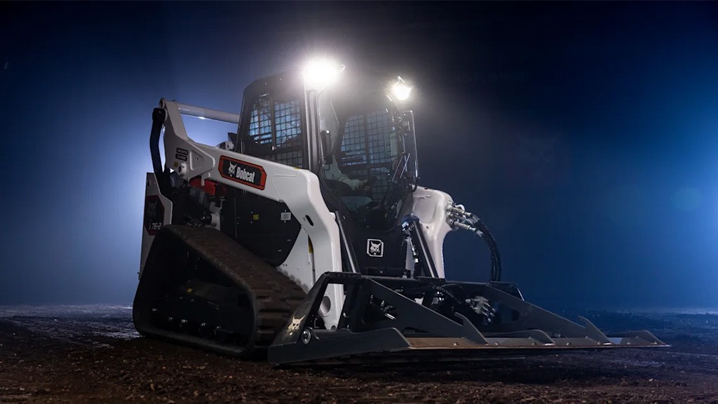 A compact track loader in dim studio lighting